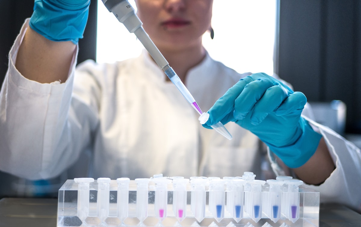 Scientist pipetting samples into test tubes at a laboratory bench